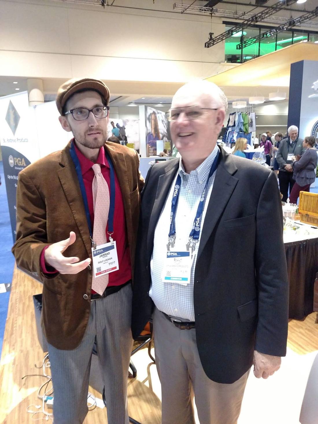 Jarrad Kogos and Billy Dettlaff standing together at a PGA trade show, both wearing PGA name badges