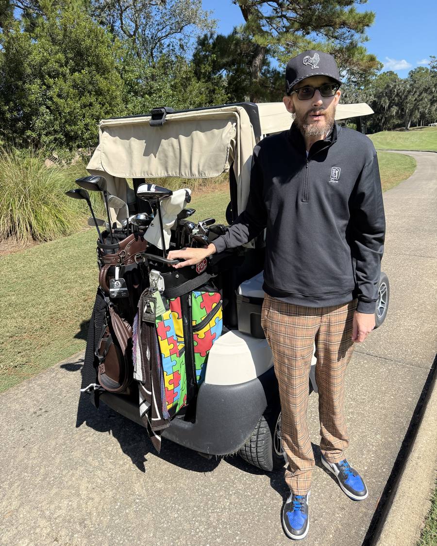 Jarrad Kogos at TPC Sawgrass beside his golf cart and his puzzle-tile golf bag
